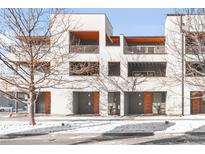 Modern three-unit building with orange doors and snowy landscaping at 2707 Decatur St, Denver, CO 80211