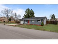 Charming ranch home featuring a red door, manicured lawn, and attached garage for convenient parking at 7906 S Dover St, Littleton, CO 80128