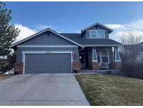 Charming two-story home with gray siding, brick accents, a covered porch, and a well-manicured front yard at 20678 E Lake Cir, Centennial, CO 80016