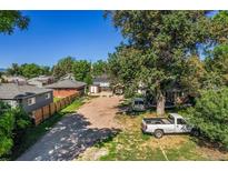Large backyard with mature trees, parking, and neighboring houses visible at 449 Lowell Blvd, Denver, CO 80204