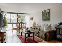 Bright living room featuring hardwood floors, modern furniture, and large windows at 1050 N Corona St # 312, Denver, CO 80218
