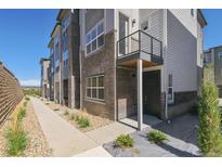 Modern townhome with brick accents, small porch, walkway and landscaping at 457 Interlocken Blvd # 101, Broomfield, CO 80021