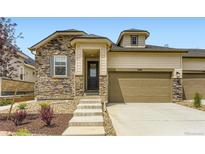 Charming home featuring a stone facade, tan siding, attached garage, and well-manicured landscaping at 3461 N Buchanan Way, Aurora, CO 80019