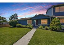 Charming blue home with a well-maintained lawn and landscaping, enhanced by a picturesque sunset sky at 10116 Quivas St, Thornton, CO 80260
