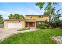 Inviting two-story home featuring an attached garage, well-maintained lawn, and mature trees at 2276 S Dover Way, Lakewood, CO 80227