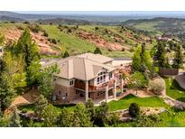 Beautiful exterior elevation of a luxury home featuring stone accents, tile roof, and a deck overlooking a mountain view at 16442 Rocky Point Ln, Morrison, CO 80465