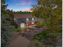 Charming two-story home with landscaped yard and inviting front porch shaded by mature trees on a sprawling lot at 1579 W Costilla Pl, Littleton, CO 80120