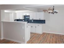 Bright kitchen with white cabinets, dark hardware, and an eat-in breakfast bar at 7255 E Quincy Ave # 205, Denver, CO 80237