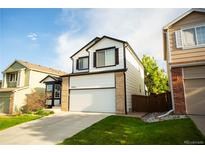 Two-story home with a two-car garage, brick accents, a well-manicured lawn and blue sky at 9950 Sydney Ln, Highlands Ranch, CO 80130
