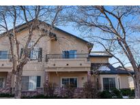 Charming multi-story home featuring a balcony, brick accents, and tan stucco exterior at 8671 E Dry Creek Rd # 721, Englewood, CO 80112