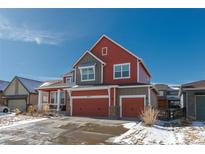 Charming two-story home featuring a two-car garage and a combination of red and gray exterior at 8775 El Diente St, Arvada, CO 80007