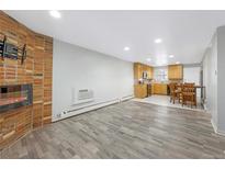 Spacious living room featuring a brick fireplace and seamless access to the adjacent kitchen and dining area at 2190 S Holly St # 207, Denver, CO 80222