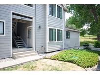 Exterior view of townhome with gray siding, well-maintained landscaping, and stair access at 10212 W 80Th Dr # C, Arvada, CO 80005