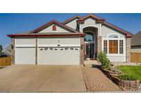 Charming two-story home featuring a spacious three-car garage and inviting brick-lined walkway at 9451 Desert Willow Trl, Highlands Ranch, CO 80129