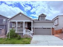 Charming gray two-story home with a covered front porch and two car garage at 9227 Salida St, Commerce City, CO 80022