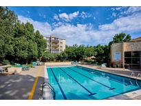 A refreshing community pool surrounded by lounging chairs and lush greenery under a bright, cloudy sky at 3465 S Poplar St # 506, Denver, CO 80224