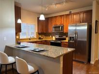 Well-lit kitchen boasts granite countertops, stainless steel appliances, and wood cabinetry at 1044 Rockhurst Dr # 208, Highlands Ranch, CO 80129