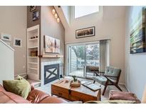 Bright living room with a fireplace, built-in shelves, and sliding glass door leading to a balcony at 3260 47Th St # 205A, Boulder, CO 80301