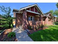 Charming brick home featuring a covered front porch and a well-manicured lawn at 737 Clayton St, Denver, CO 80206