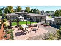 Landscaped backyard features a well-manicured lawn, pergola, a fire pit, and an outdoor seating area at 3299 S Newcombe St, Lakewood, CO 80227