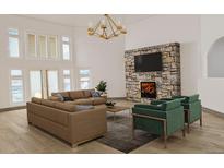 Bright living room with a stone fireplace, high ceilings, and modern chandelier at 3299 S Newcombe St, Lakewood, CO 80227