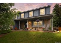 Charming two-story home featuring brick accents, a covered porch with rocking chairs, and a well-manicured lawn at 9963 W Canyon Ave, Littleton, CO 80127