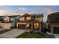 Charming two-story home with a welcoming front porch and well-manicured lawn at dusk at 3636 Sublime Ct, Castle Rock, CO 80108