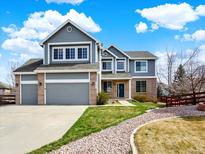 Charming two-story home featuring a manicured lawn, brick accents, and a spacious three-car garage at 6094 Terry Ln, Arvada, CO 80403