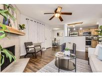 Inviting living room featuring a fireplace, ceiling fan, wood floors, and an open concept layout at 14602 E 2Nd Ave # 303C, Aurora, CO 80011