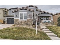Beautiful two-story home featuring stone accents, gray siding, and a welcoming front porch at 3880 Fairbrook Pt, Highlands Ranch, CO 80130