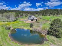 Idyllic property featuring a serene pond with swans and a beautifully landscaped home nestled in a lush, green setting at 20101 Spring Gulch Rd, Morrison, CO 80465