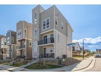 Modern three-story townhome with gray siding, stone accents, black railings, and a well-maintained front yard at 11400 W Grand Ave, Littleton, CO 80127