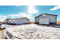 Gray manufactured home with detached garage on snowy lot at 43620 E 80Th Ave, Bennett, CO 80102