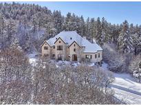 Snow-covered home with a large yard, nestled in a wooded area at 1043 Meteor Pl, Castle Rock, CO 80108