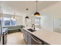 Bright kitchen features a center island with stainless steel appliances and modern pendant lighting at 3201 Albion St, Denver, CO 80207