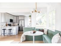 Bright kitchen features white cabinets, stainless steel appliances, breakfast bar and attached dining area with built in bench seating at 3201 Albion St, Denver, CO 80207