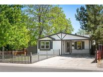 Charming home featuring gray and white exterior paint, well-maintained landscaping, and a fenced yard at 1522 Willow St, Denver, CO 80220
