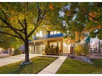 Charming two-story home with a well-manicured lawn, mature trees, and covered front porch at 16456 Wagon Pl, Parker, CO 80134