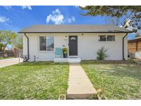 Charming single-story home featuring a black front door, well-maintained lawn, and white painted brick at 7001 Alan Dr, Denver, CO 80221