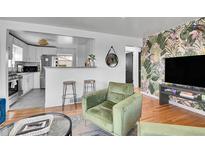 Open-concept living room with kitchen view, modern decor, hardwood floors, and cozy seating at 7001 Alan Dr, Denver, CO 80221