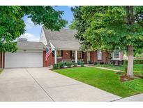 Charming brick home featuring a well-manicured lawn, mature trees, and an inviting covered front porch at 3450 E Easter Ave, Centennial, CO 80122