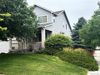 Charming two-story home featuring a well-maintained lawn, mature trees, and a welcoming front porch at 11499 Kenton St, Commerce City, CO 80640
