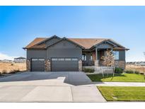 A beautifully landscaped home showcasing stone accents, a three-car garage, and a welcoming front porch at 23774 E 36Th Pl, Aurora, CO 80019