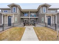 Charming exterior view of a two-story townhome with a balcony and fenced front yard with walkway at 330 High Point Dr # B102, Longmont, CO 80504