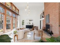 Bright living room featuring floor-to-ceiling windows, modern furniture, and a prominent brick fireplace at 6110 E 6Th Avenue Pkwy, Denver, CO 80220