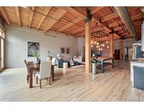 Bright, open living room with exposed wood beams, dining area, brick accent wall, and modern decor at 2955 Inca St # 2D, Denver, CO 80202