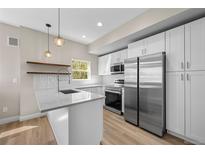 Bright kitchen features stainless steel appliances, white cabinets, granite countertops, and pendant lighting at 2140 S Ash St # 105, Denver, CO 80222