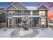 Charming townhome showcasing a snow covered yard, covered porch, and eye-catching blue siding with stone accents at 14693 E Crestridge Dr, Aurora, CO 80015