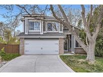 Charming home featuring a two-car garage, gray siding, brick accents and a well-maintained lawn at 9523 Sherrelwood Ln, Highlands Ranch, CO 80126