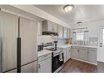Updated kitchen features stainless steel refrigerator, range, grey cabinets and hardwood floors at 8160 Washington St # 67, Denver, CO 80229